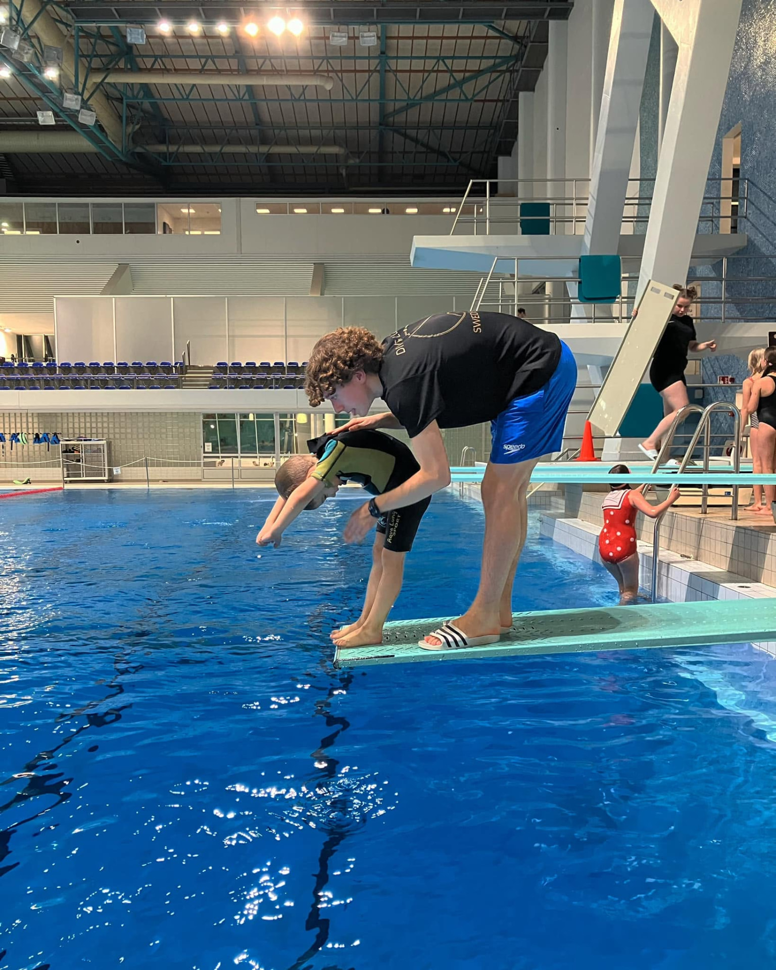 A coach carefully supports a child on the one-metre springboard